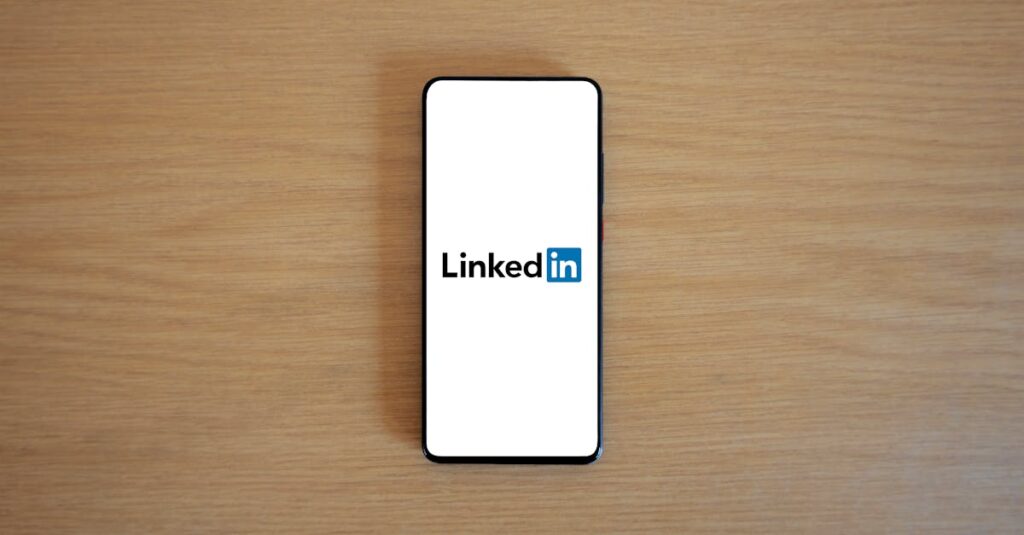 Top view of a smartphone displaying the LinkedIn logo on a wooden surface.